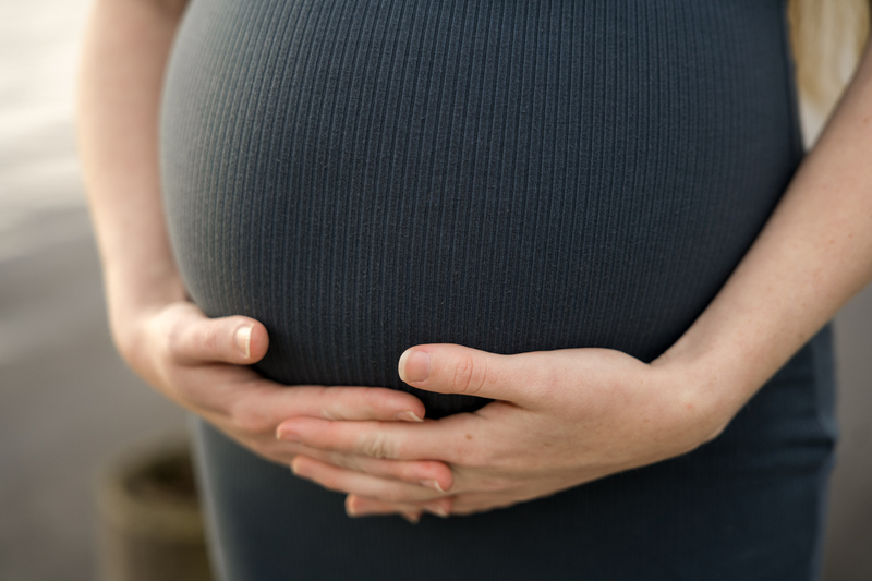 Schwangere Frau hält ihren Bauch.